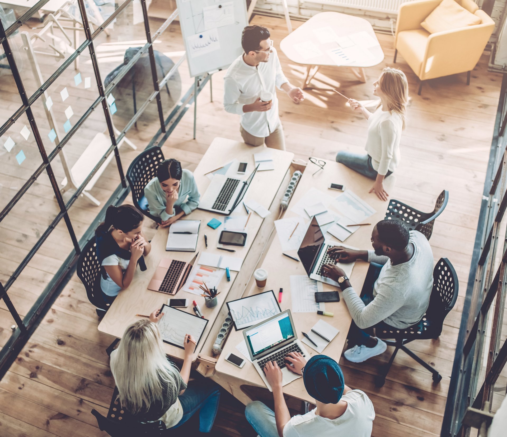 g.a.s.t.-Akademie: Fort- und Weiterbildung | iStock Das Imagebild illustriert die g.a.s.t.-Akademie. Es zeigt eine Gruppe junger Menschen, die zusammen an einem Tisch arbeiten. Auf dem Tisch stehen Laptops, Papier, Schreibmaterialien und Getränke sind auf der Arbeitsplatte verteilt.